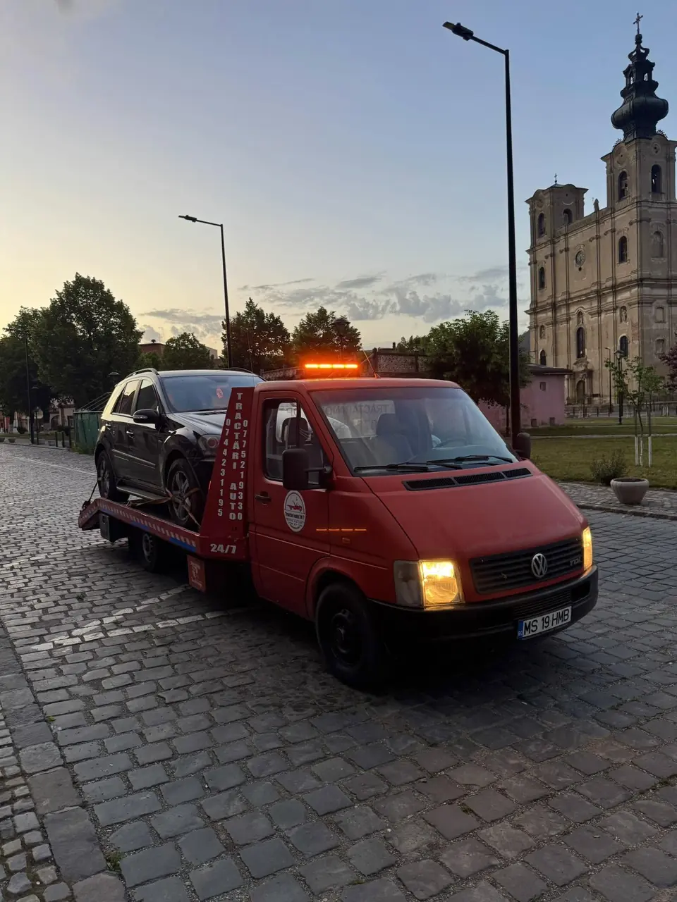 Platforma noastră roșie, cu girofarul aprins, în fața bisericii din centrul Reghinului