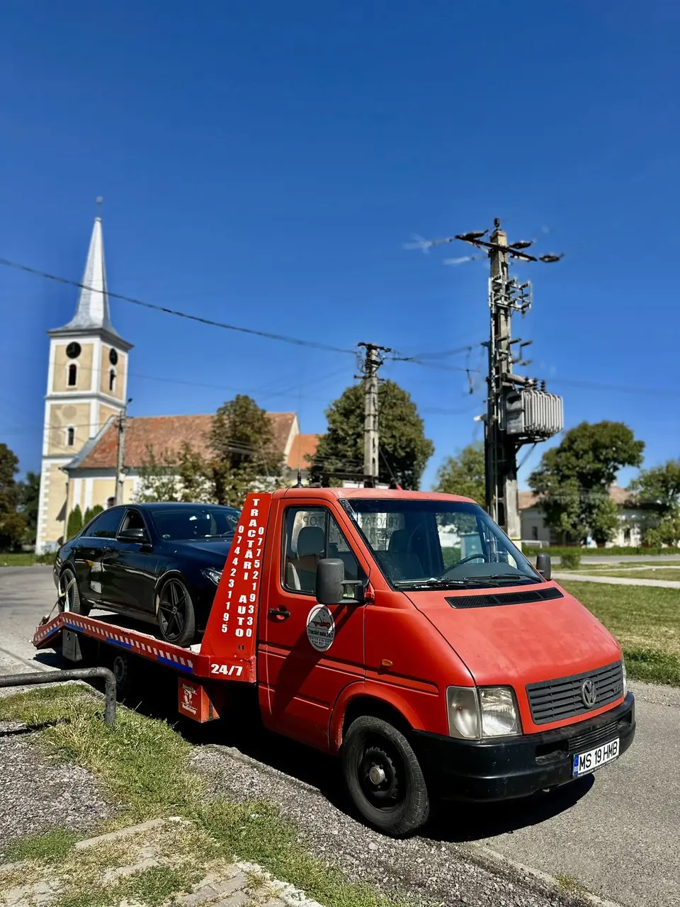 Platforma încărcată, oprită lângă o biserică, într-o zi senină
