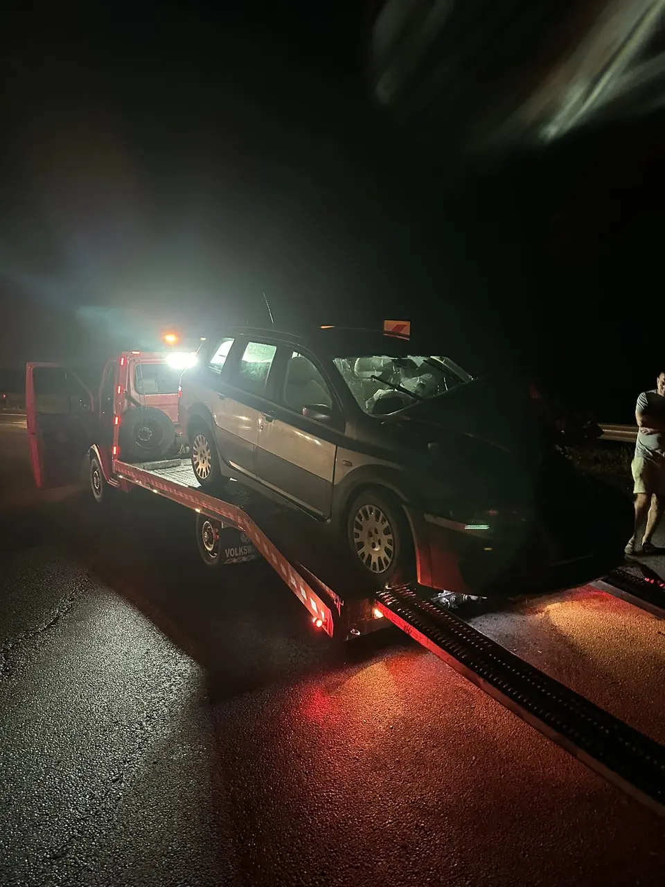 Mașină trasă pe rampe noaptea, cu lumină roșie de la stopuri
