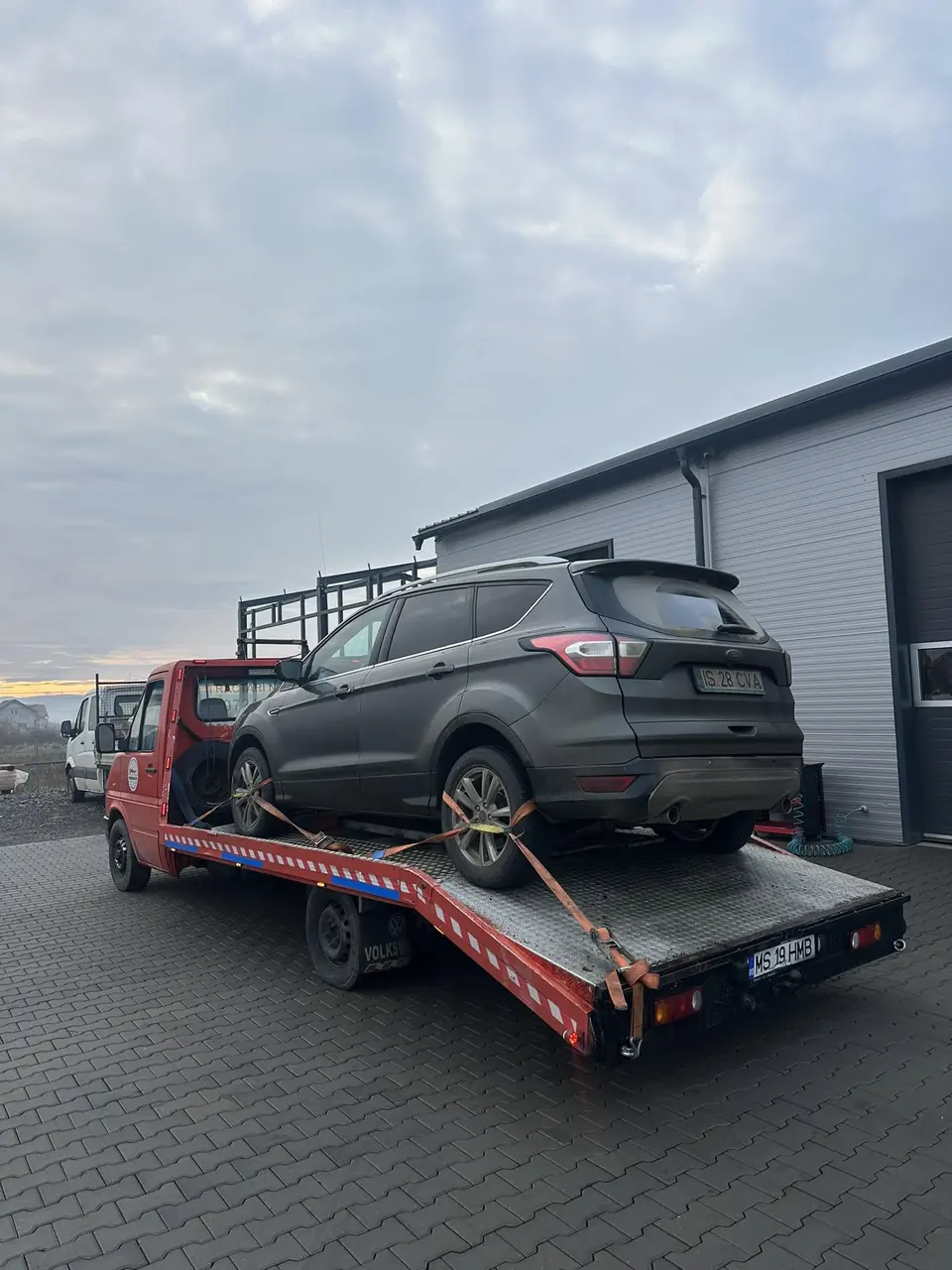 SUV gri urcat pe platformă, în fața unei hale